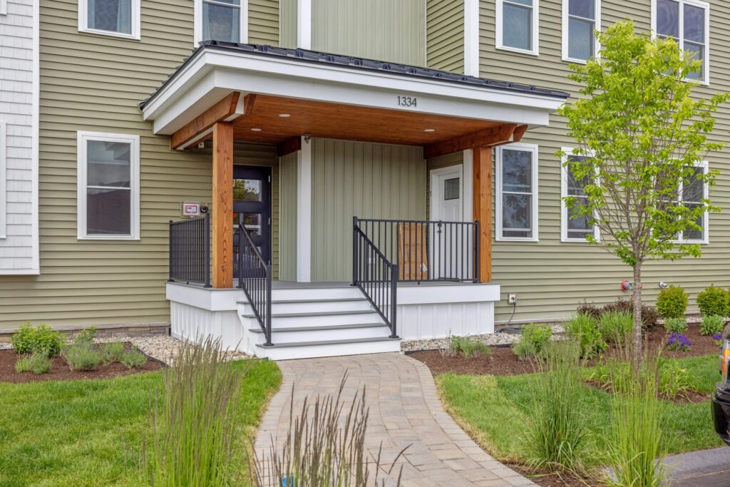 front entrance to an apartment with large green siding and two story entry